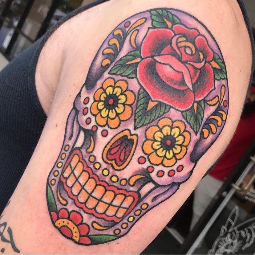 a woman has a sugar skull tattoo on her arm