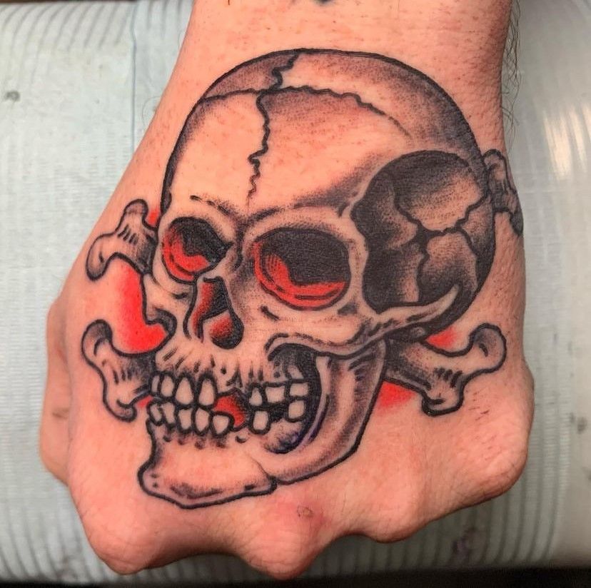 a person has a tattoo of a skull and crossbones on their hand