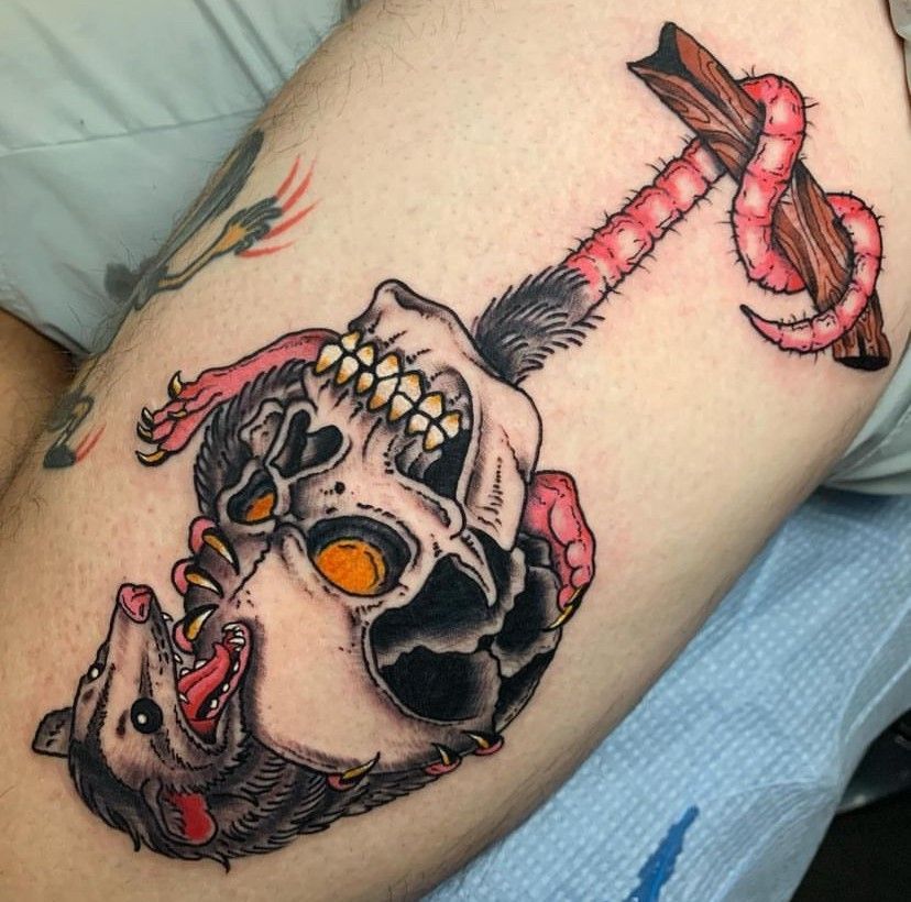 a tattoo of a skull with an opossum hanging from it