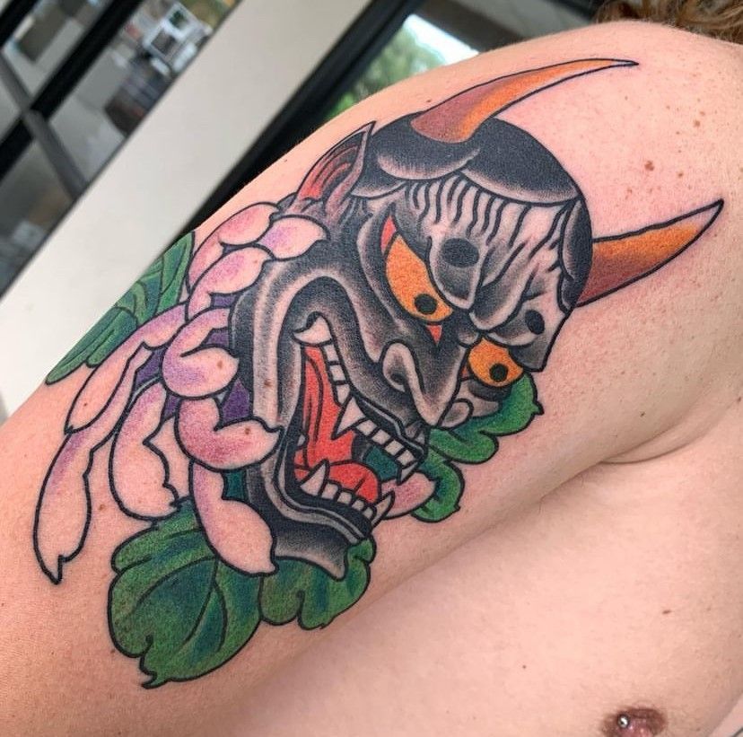 a tattoo of a demon head with horns and flowers