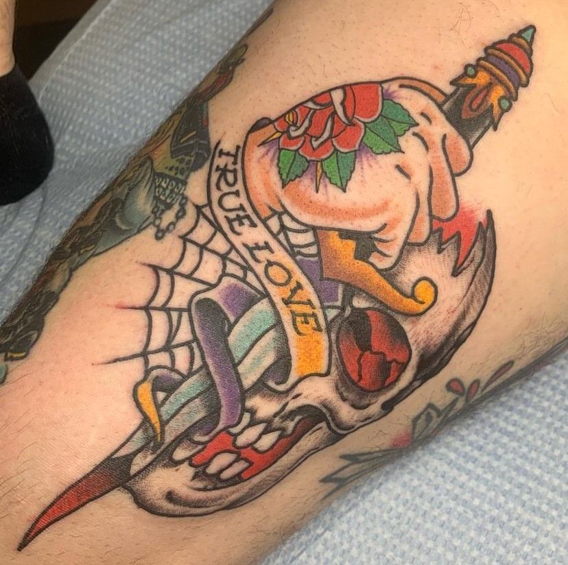 a tattoo of a skull with a dagger and a banner that says true love