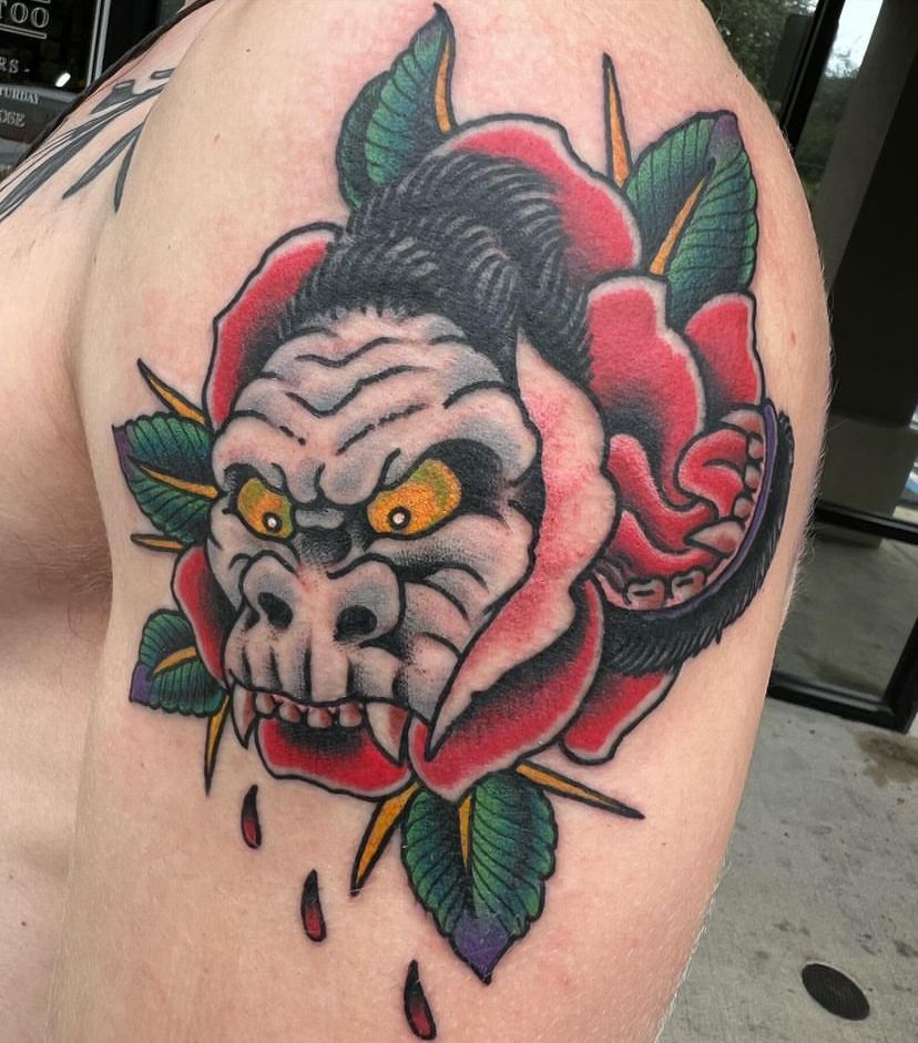 a man has a tattoo of a gorilla and a rose on his shoulder