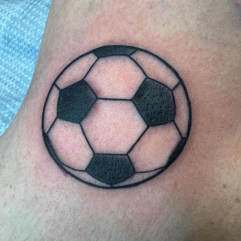 a person has a tattoo of a soccer ball on their ankle
