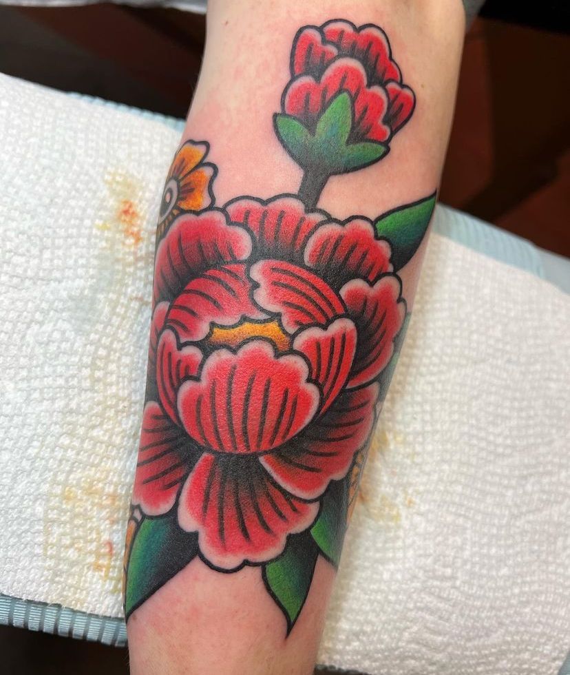 a person has a tattoo of a red flower on their forearm