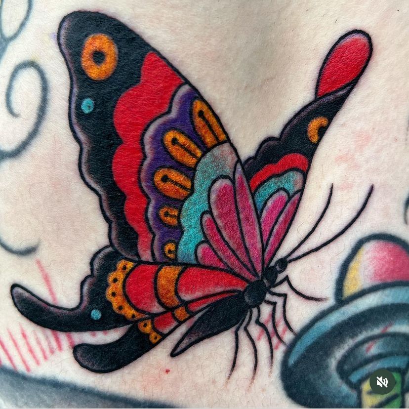 a close up of a colorful butterfly tattoo on a person's back