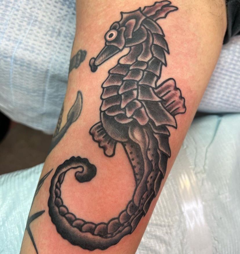 a person has a tattoo of a seahorse on their arm