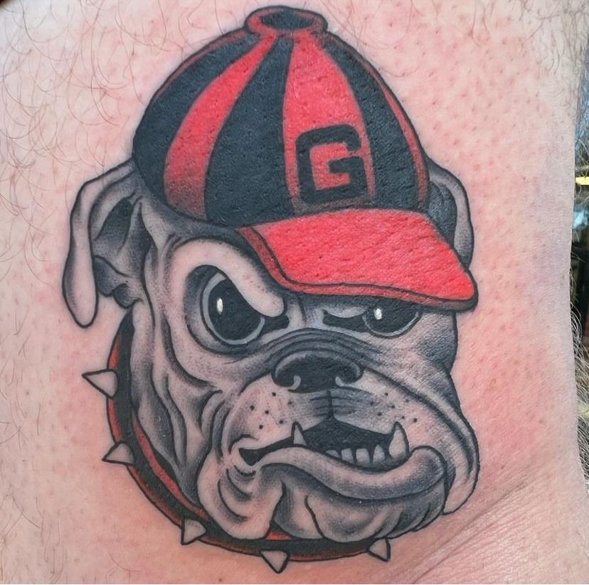 a tattoo of a bulldog wearing a hat with the letter g on it