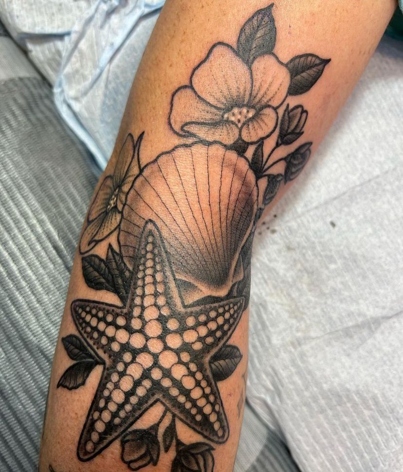 a tattoo of a starfish, seashell and flowers on a person's arm