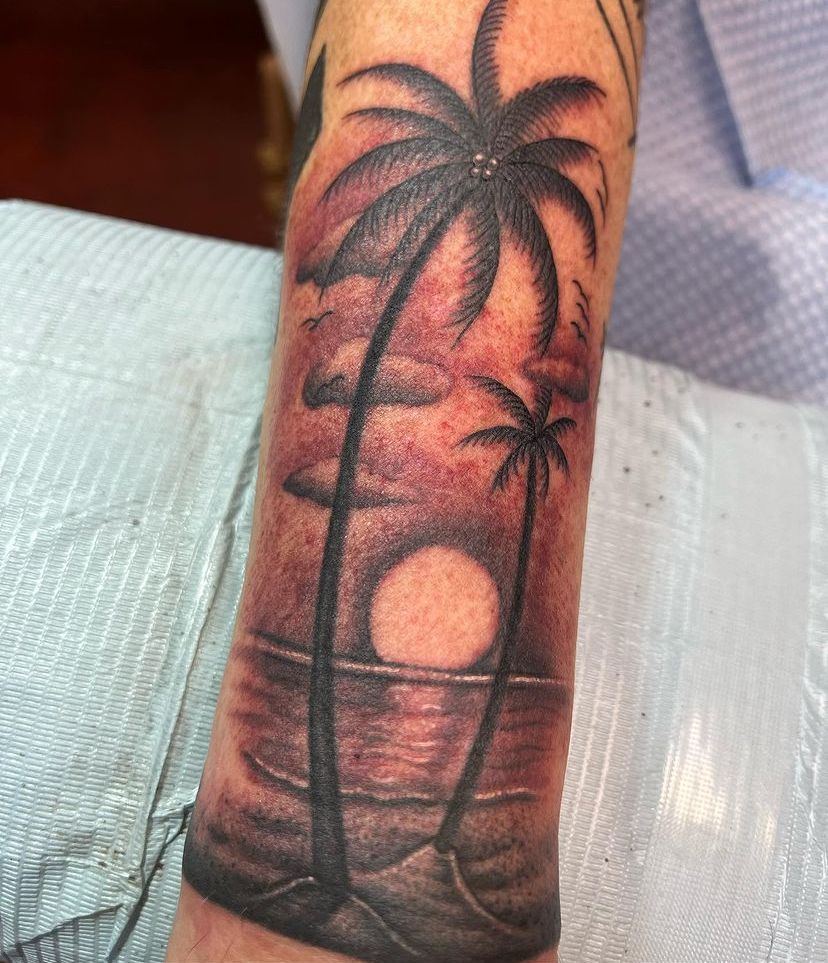 a man has a tattoo of palm trees on his arm