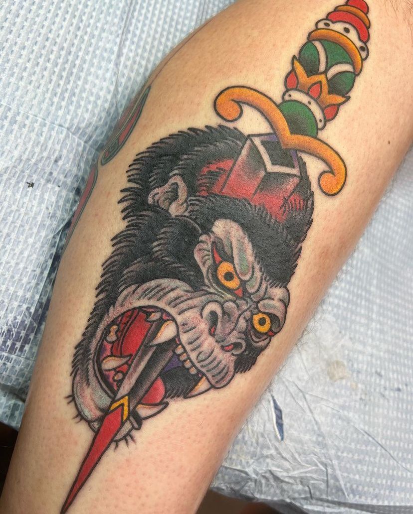 a tattoo of a gorilla with a dagger in its mouth