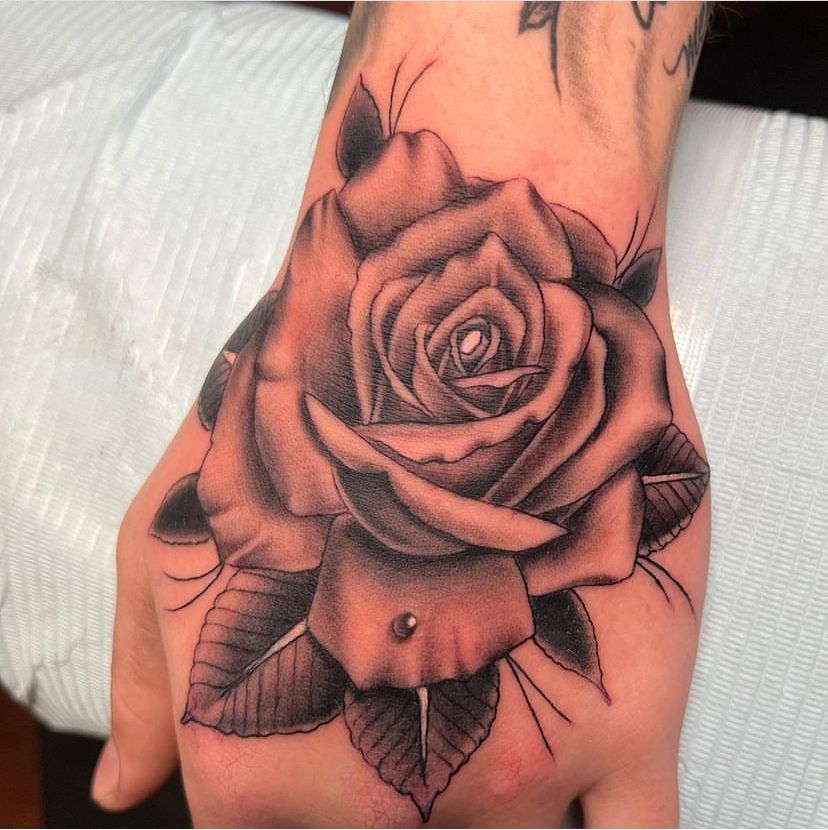 a person has a tattoo of a rose on their hand