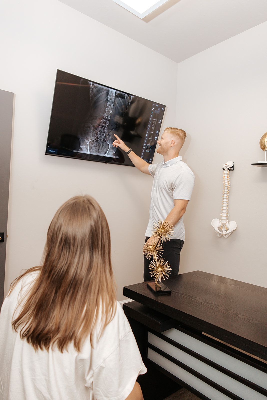Massage therapists working on a client in a clinic room with treatment tables and wall clock