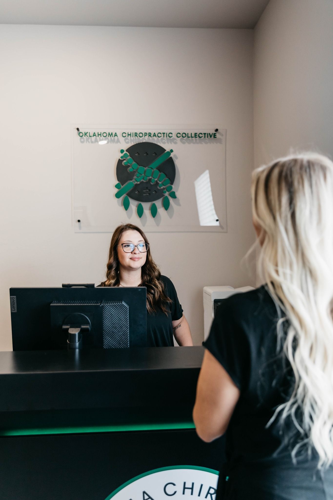 Reception desk with two women, one seated behind the counter and one standing in the foreground