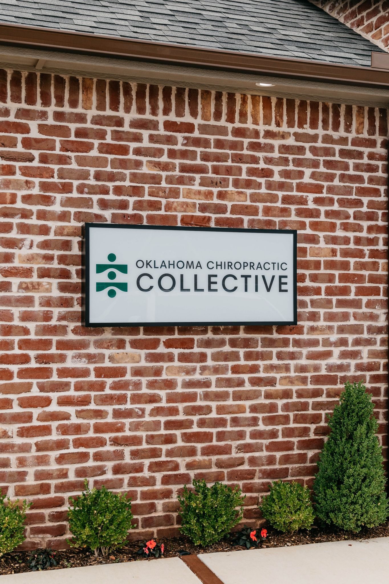 Sign for The Joint Chiropractic Collective on a brick wall outside a building