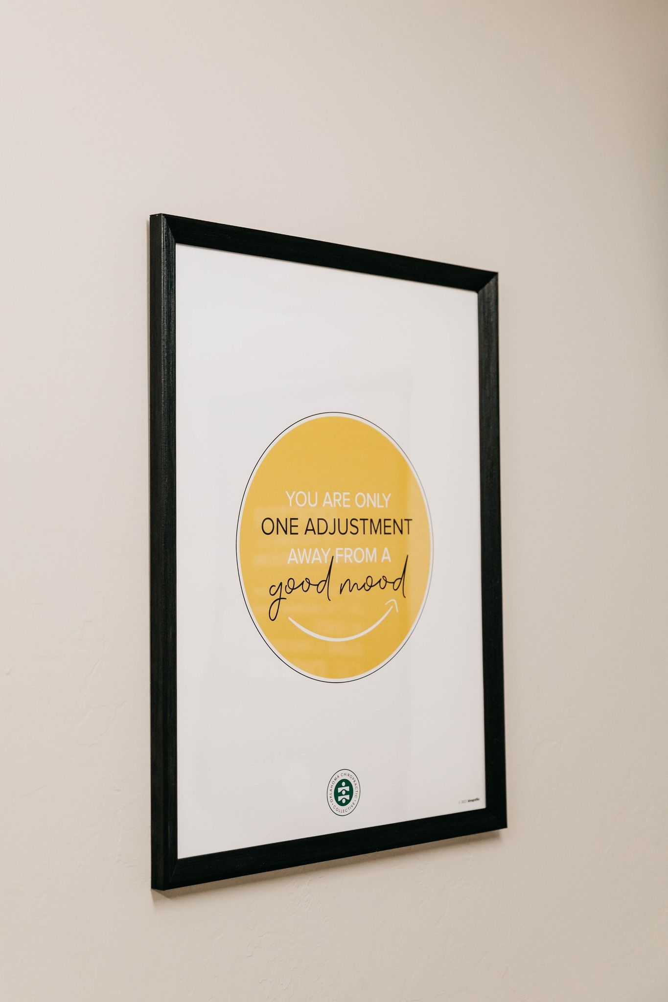 Framed certificate with a yellow seal, hanging on a beige wall.