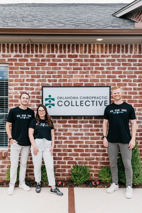 Three people standing by a brick wall with a “Collective” sign outdoors.