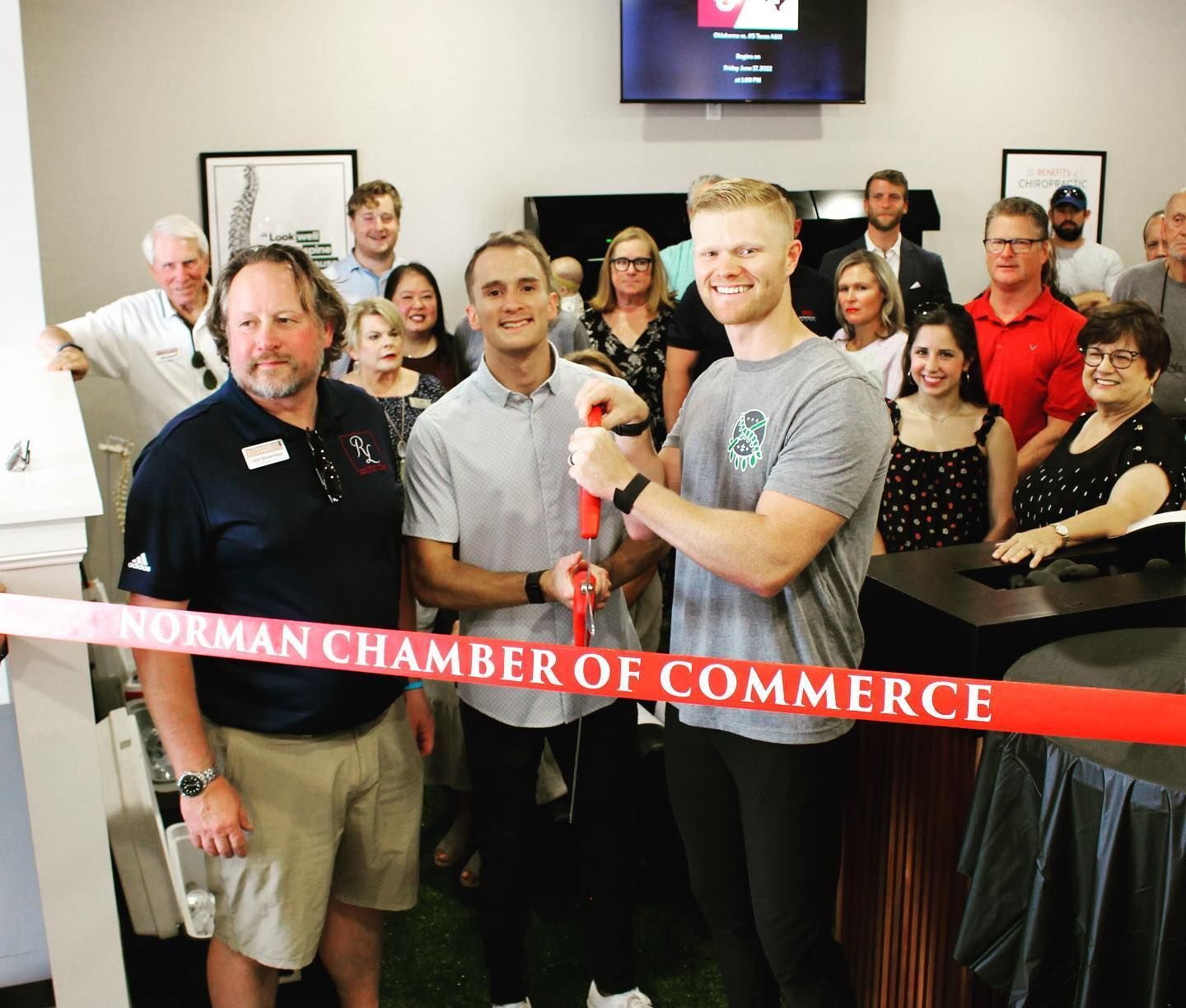 Ribbon-cutting ceremony with smiling crowd at Norman Chamber of Commerce event