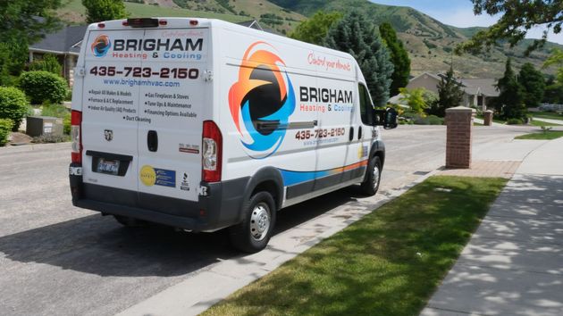 Brigham plumbing van parked on a residential street with mountains in the background