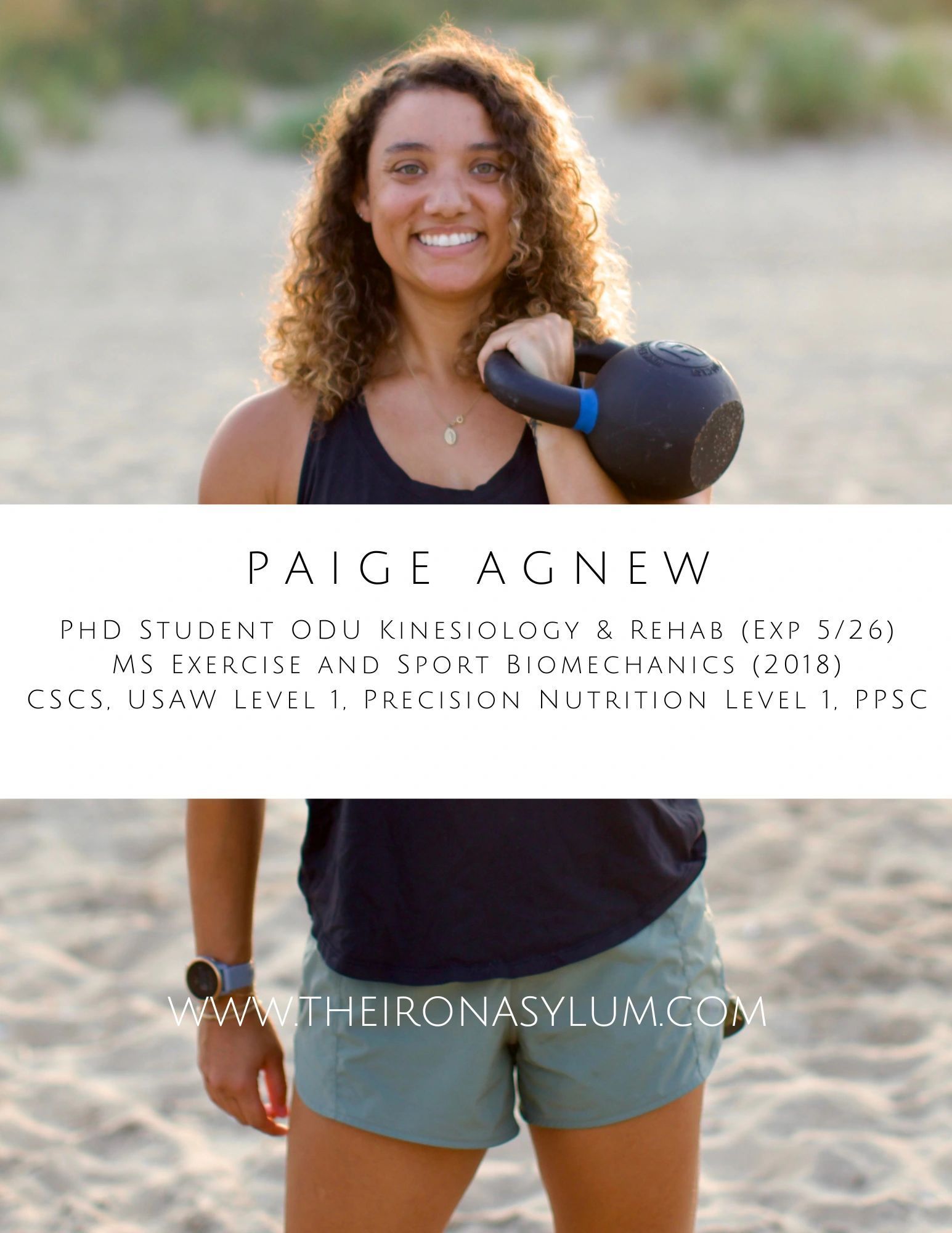 A woman is standing on a beach holding a kettlebell.