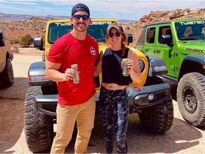 A man and a woman are posing for a picture in front of jeep 's.