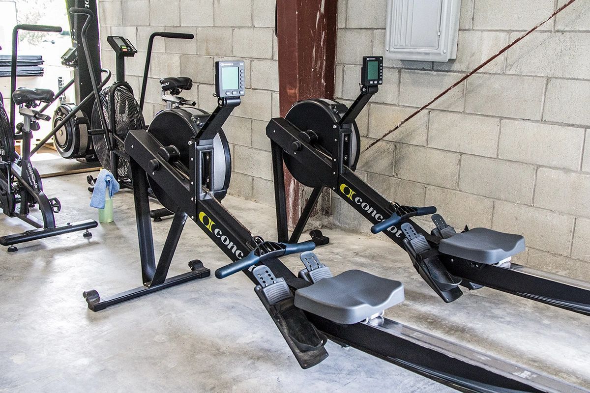 Two rowing machines are sitting next to each other in a gym.