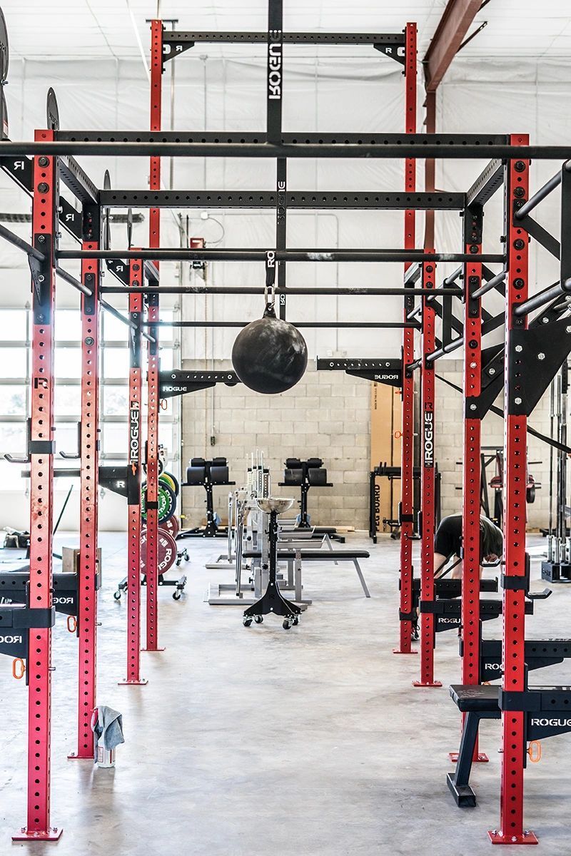 A gym with a lot of equipment and a boxing ball hanging from the ceiling.
