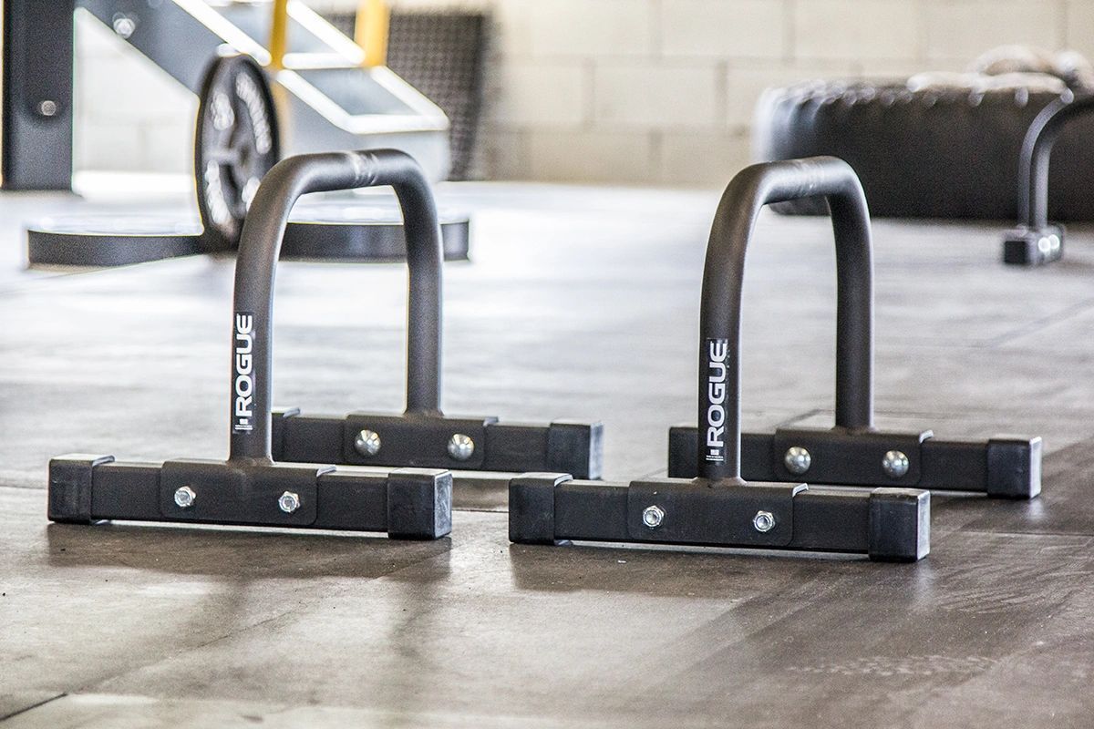 A pair of parallel bars are sitting on the floor in a gym.