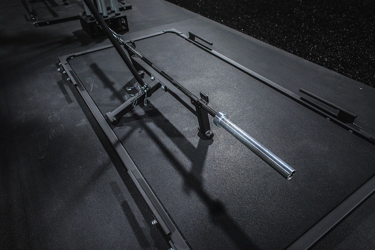 A black and white photo of a barbell on a mat in a gym.