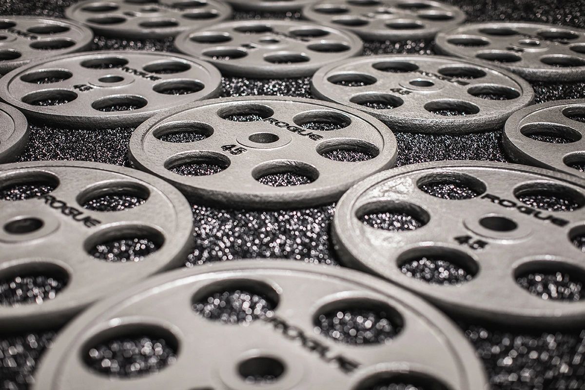 A bunch of weight plates are sitting on the floor.