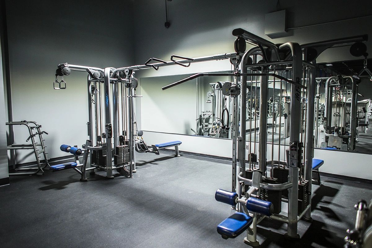 A gym filled with lots of exercise equipment and a large mirror.
