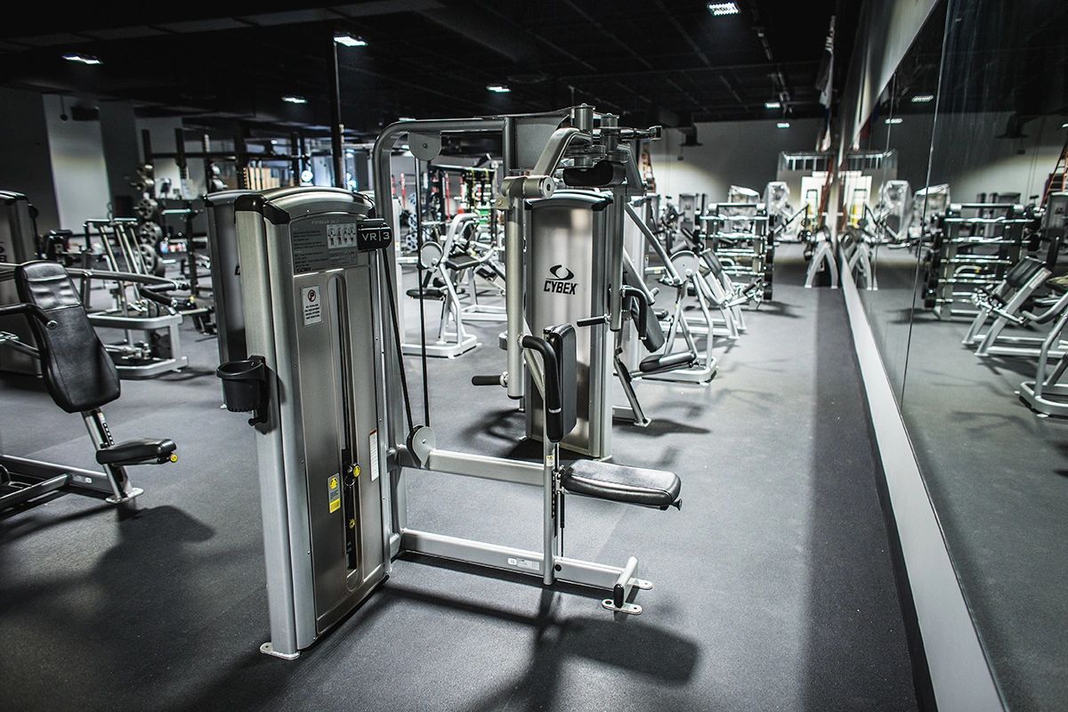 A gym filled with lots of exercise equipment and a large mirror.
