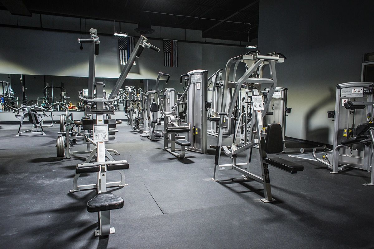 A gym filled with lots of exercise equipment and a large mirror.