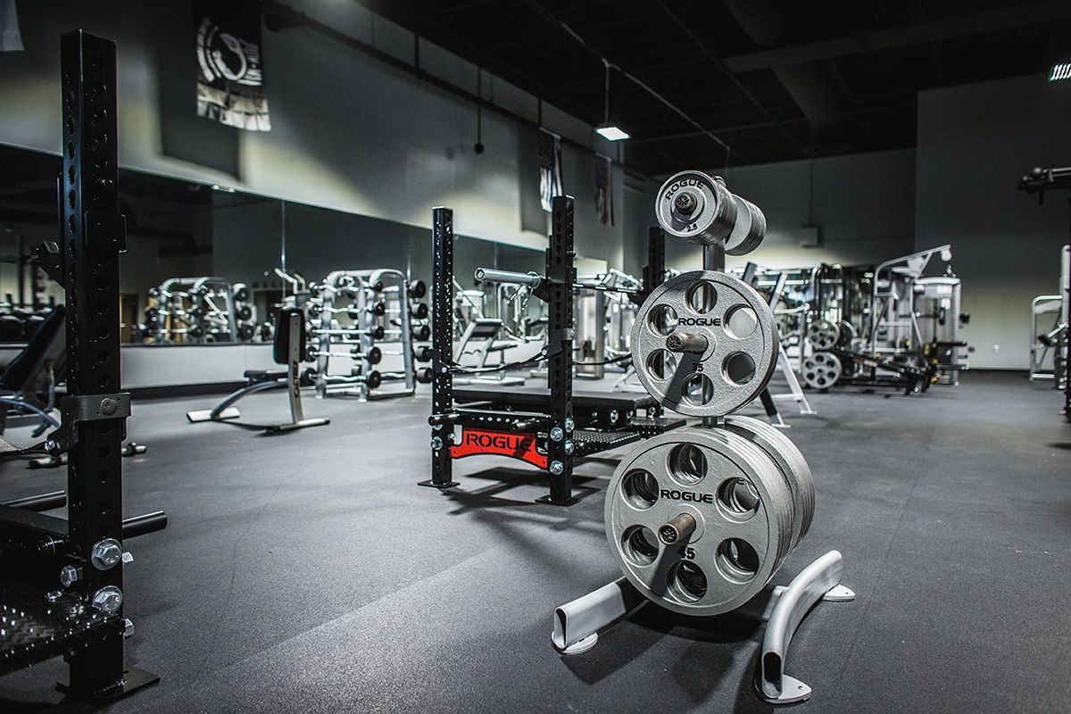 A gym filled with lots of exercise equipment and a barbell rack.