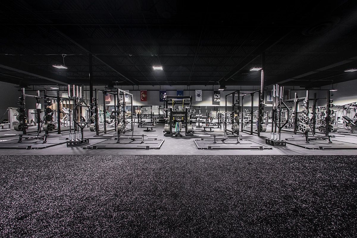 A black and white photo of a gym filled with lots of exercise equipment.