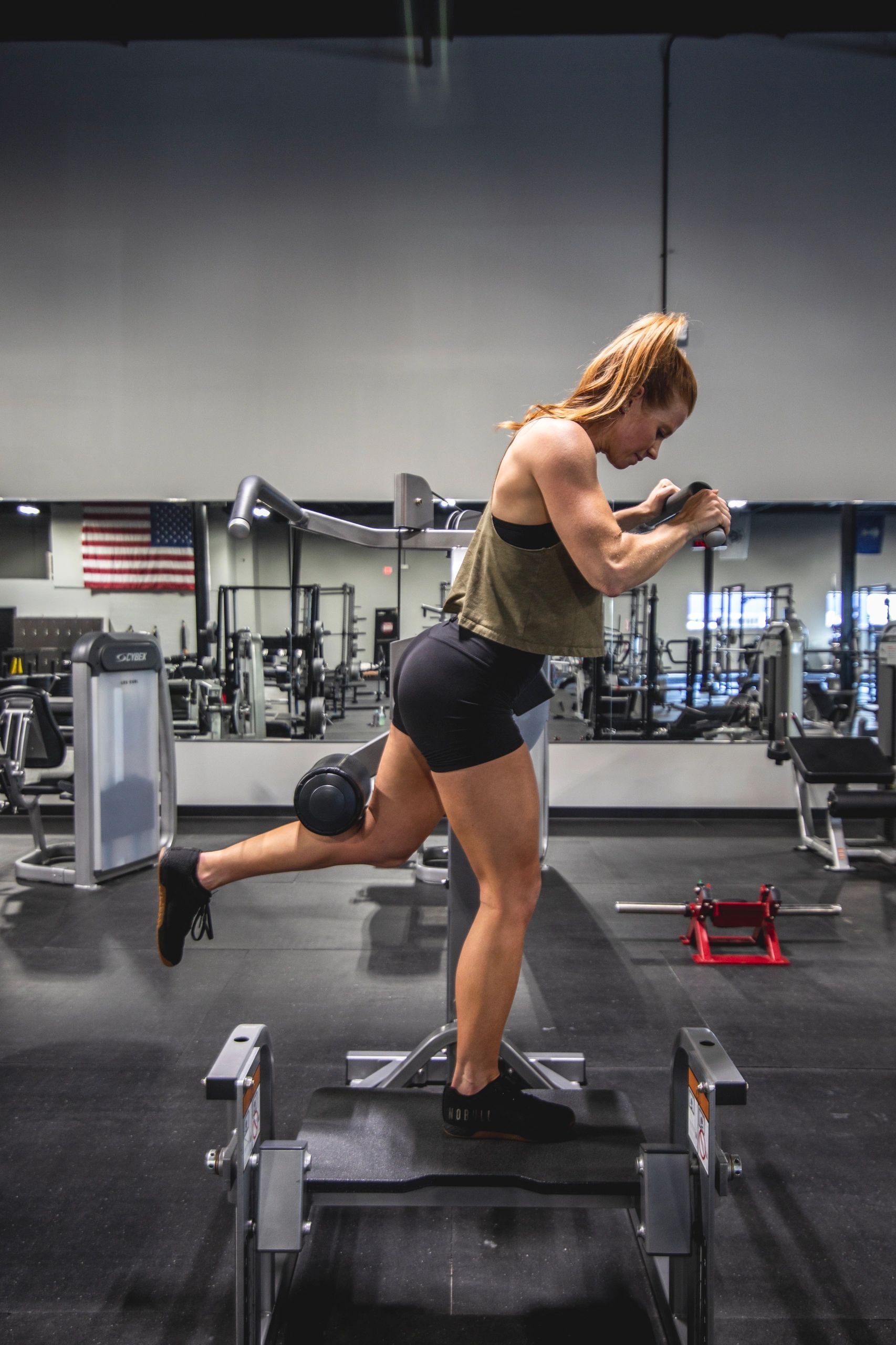 A woman is doing squats on a machine in a gym.