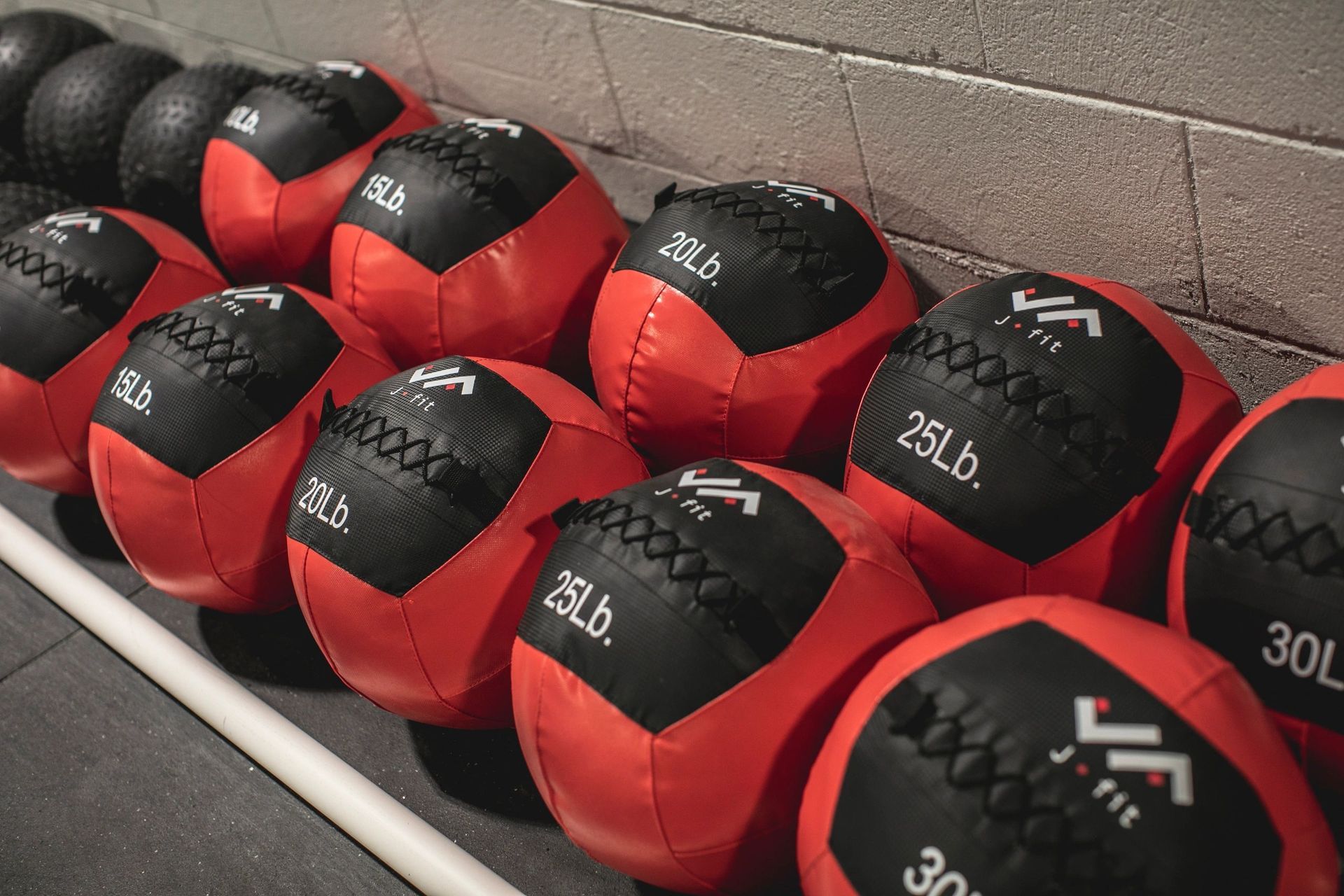A row of red and black medicine balls are lined up on a shelf.