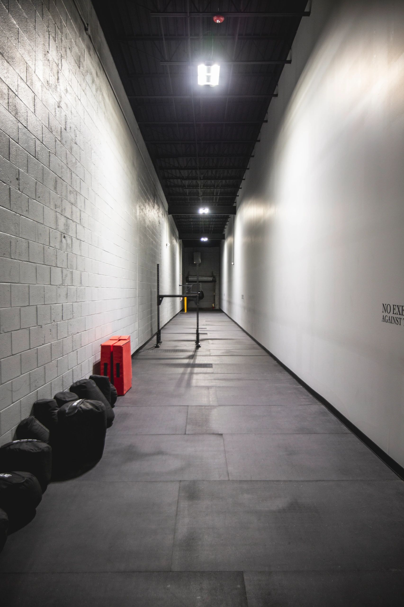 A long hallway with a bunch of dumbbells on the floor.