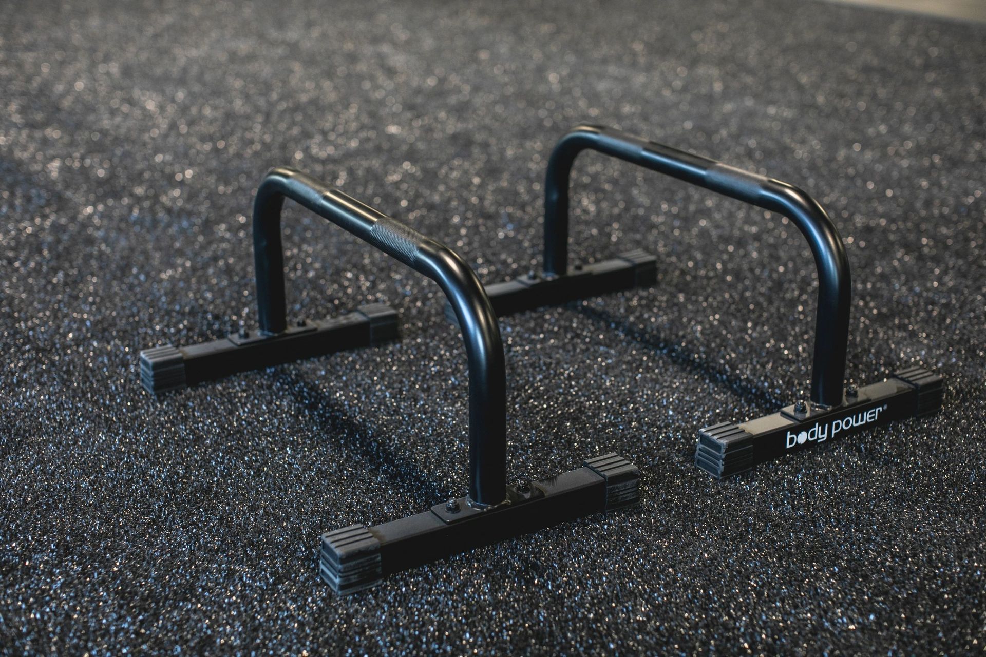 A pair of parallel bars sitting on top of a rubber floor.