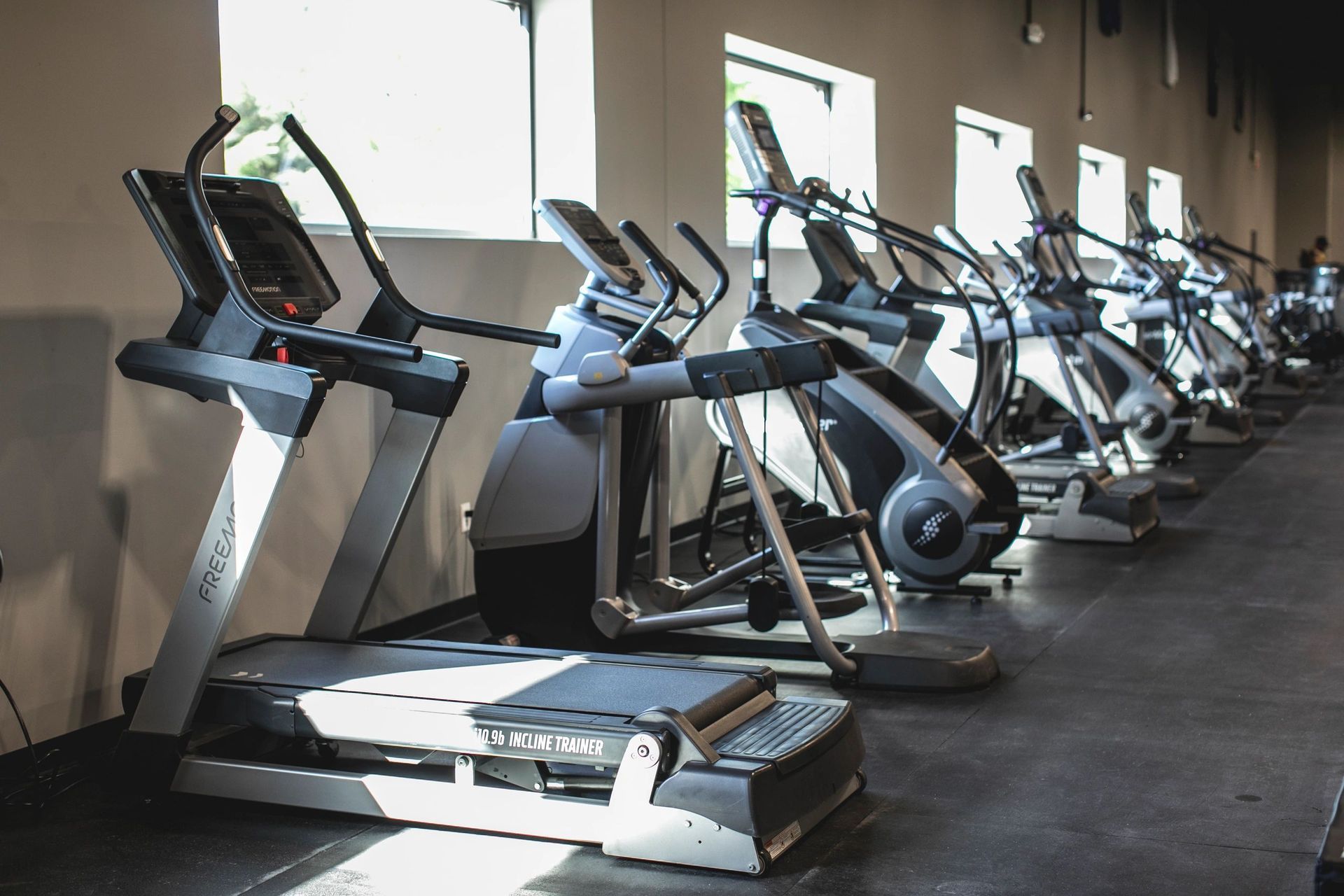 A row of treadmills are lined up in a gym.