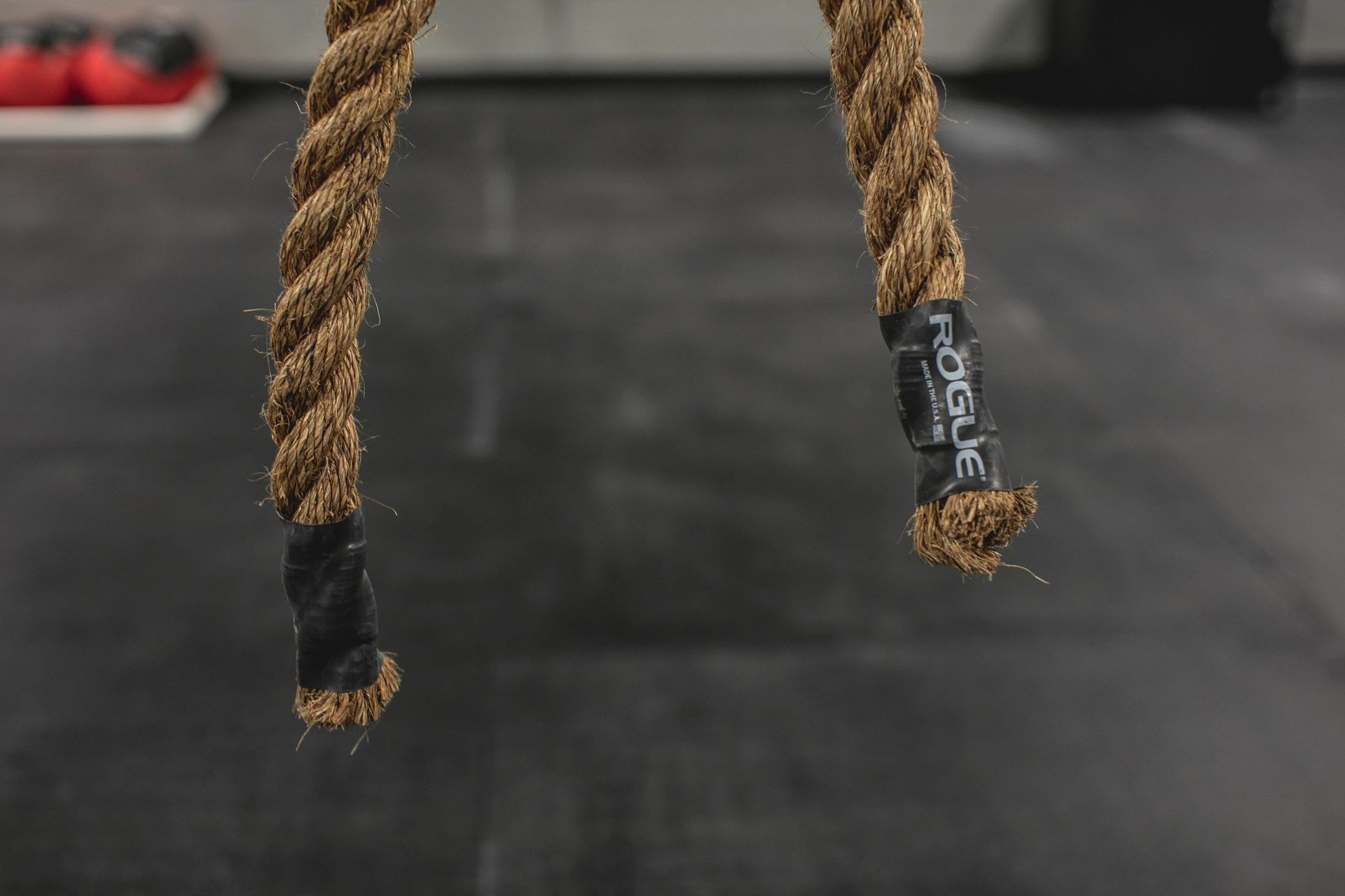 A close up of two ropes hanging from a wall in a gym.