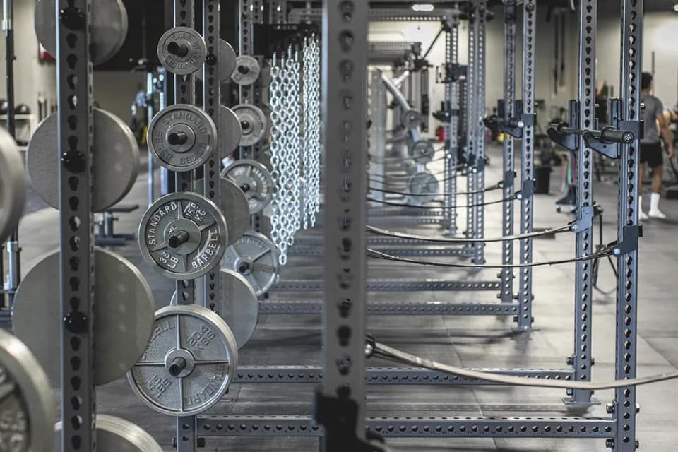 A row of squat racks filled with weights in a gym.