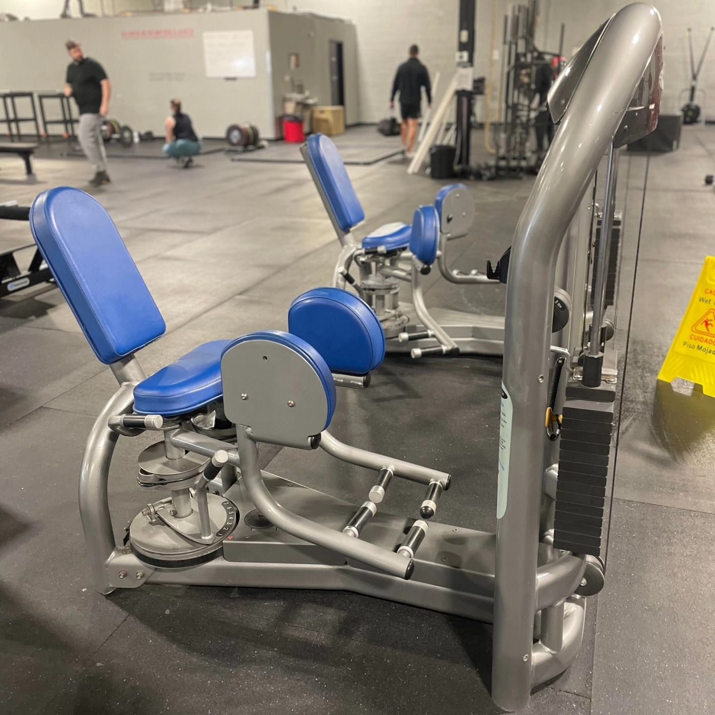A gym with a yellow caution sign on the floor