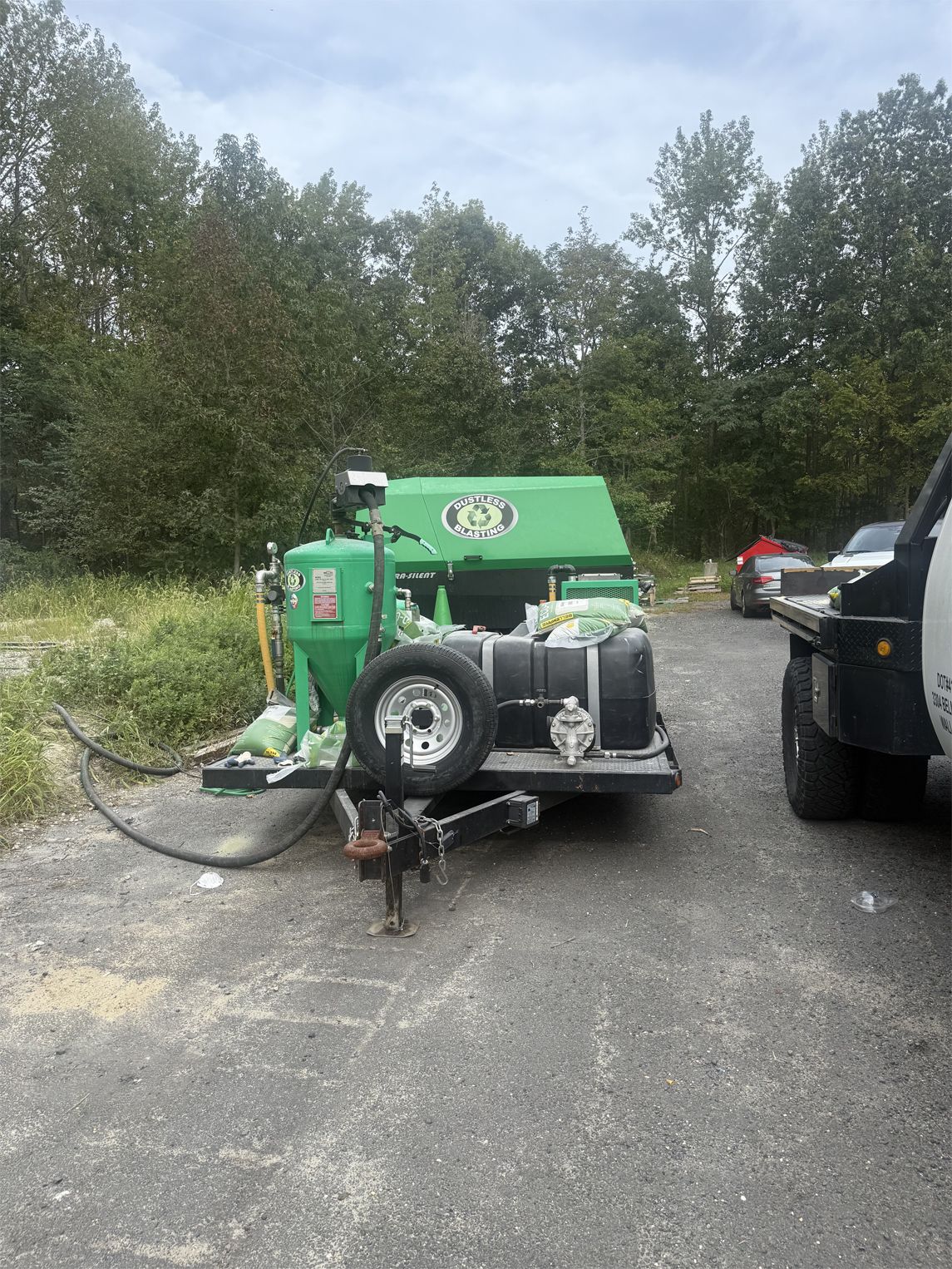 Green construction equipment trailer, outdoors, parked on gravel.