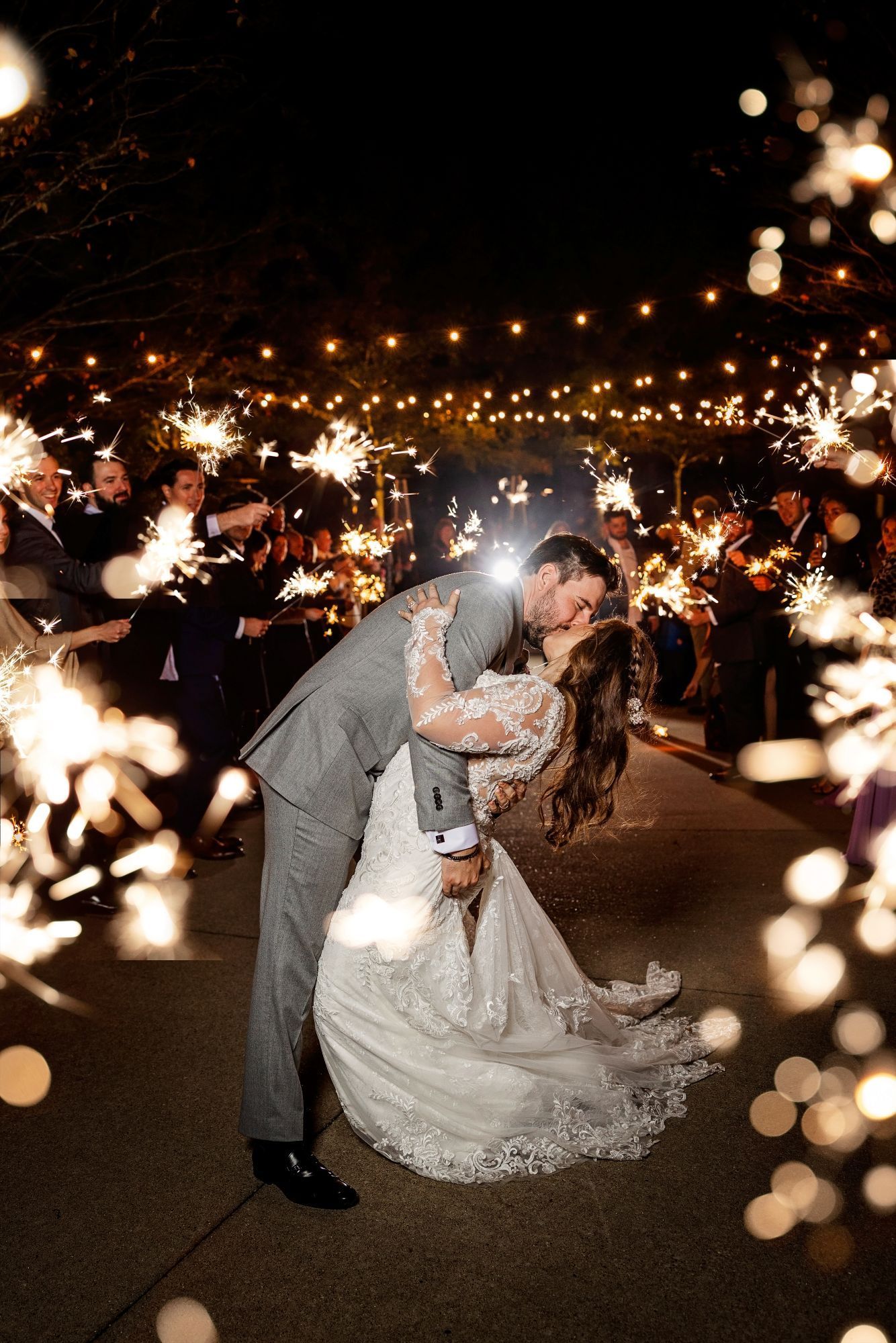 Bride and groom kissing during a sparkler send-off at an outdoor evening wedding.