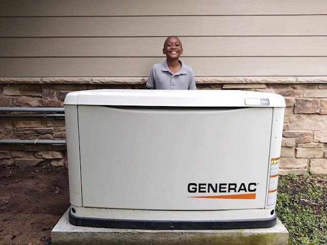 a boy is standing next to a generac generator outside of a house .