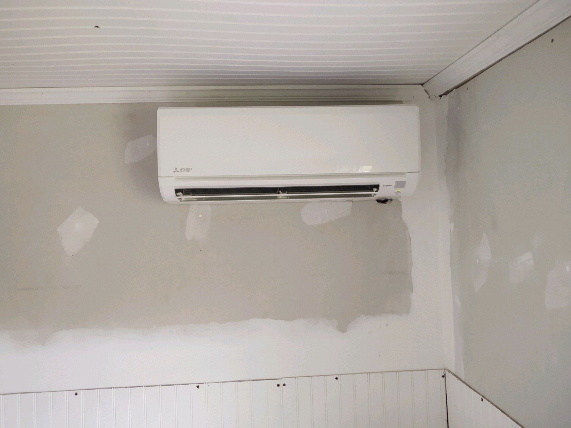 a white air conditioner is hanging on a wall in a room .