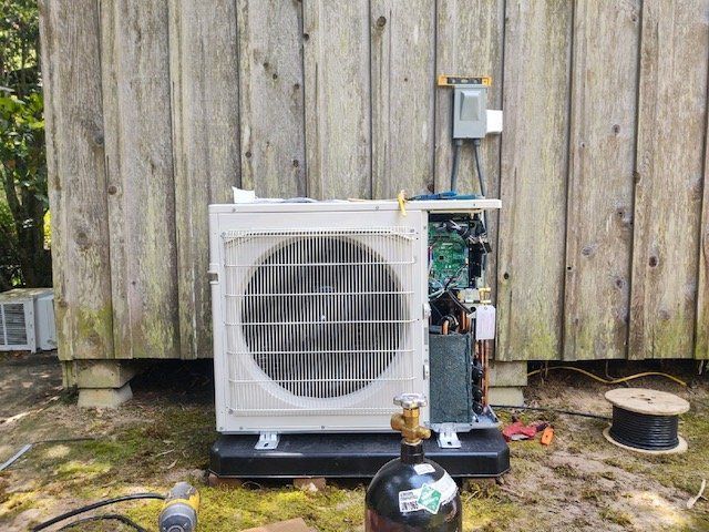 a white air conditioner is sitting in front of a wooden building .