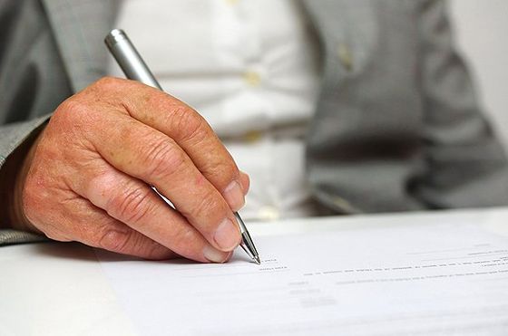 Hand of old woman signing the document