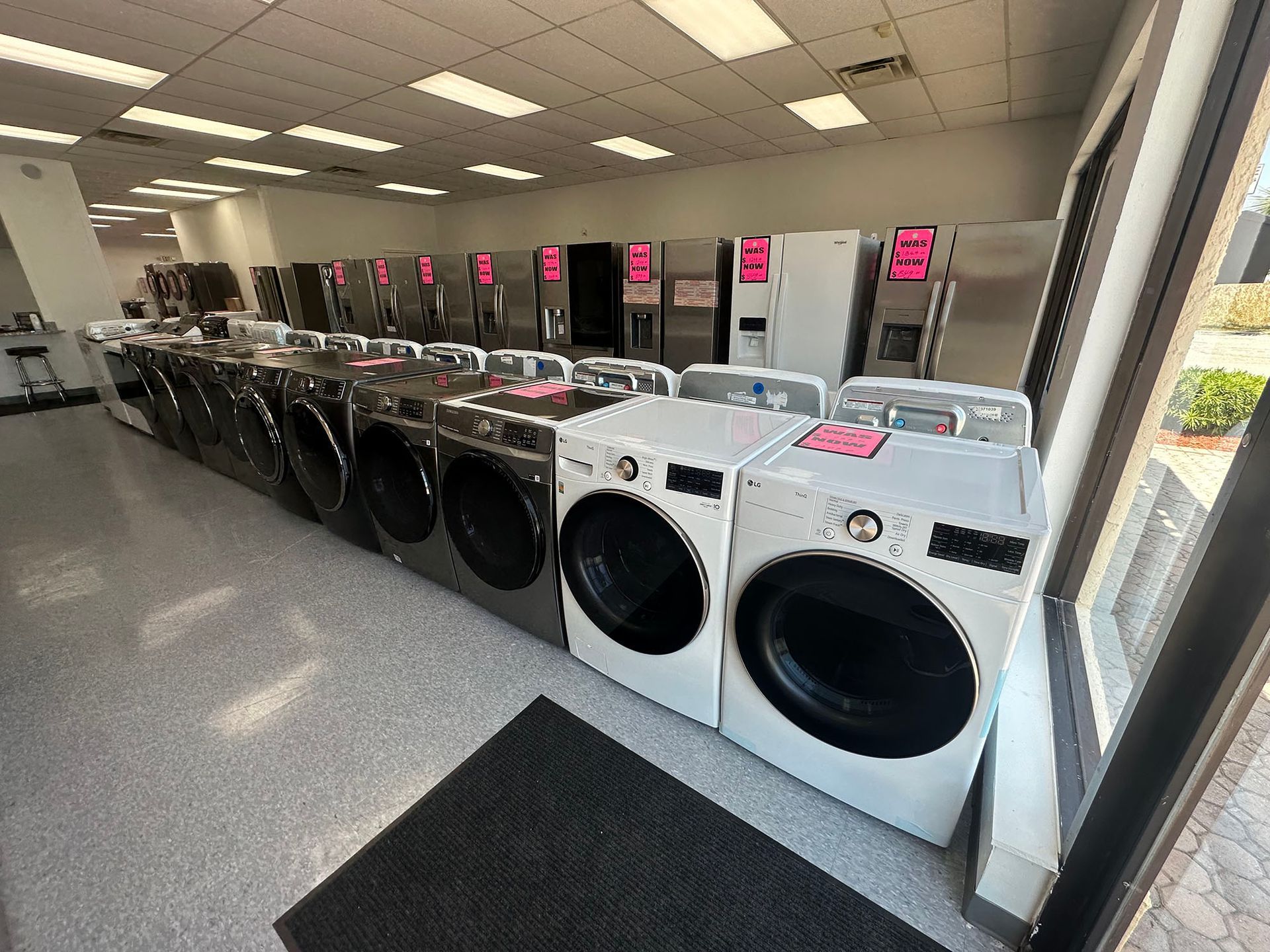 A row of washers and dryers are lined up in a store.