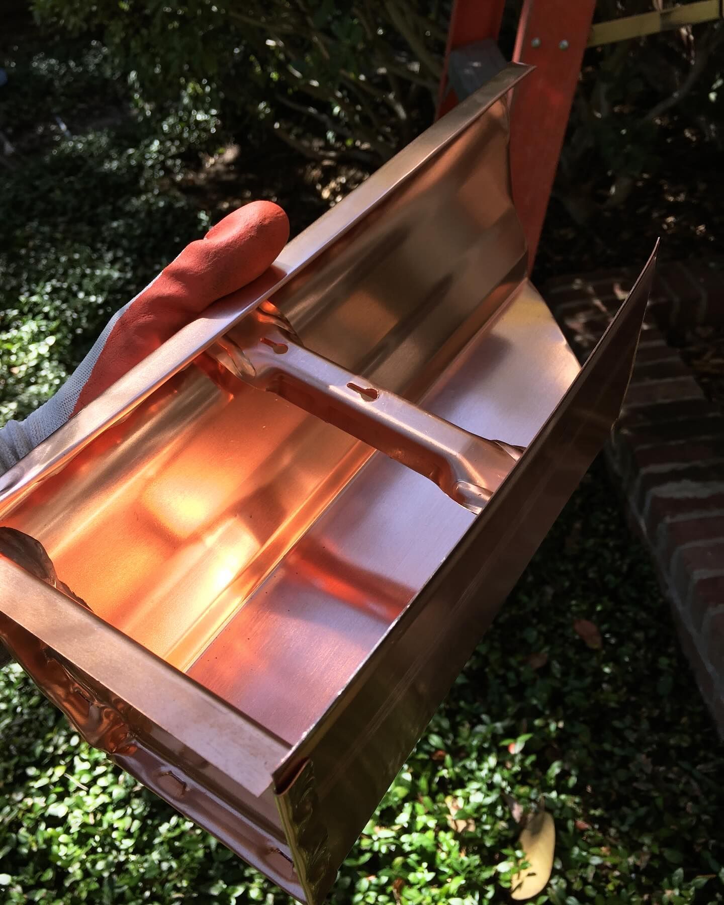 A person is holding a copper gutter in their hand